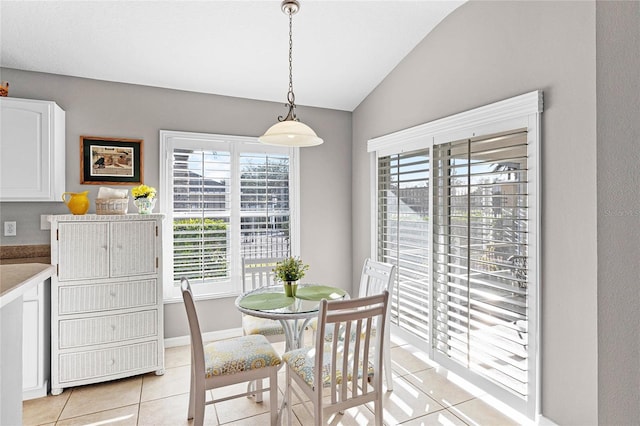 dining space with light tile patterned floors, lofted ceiling, and baseboards