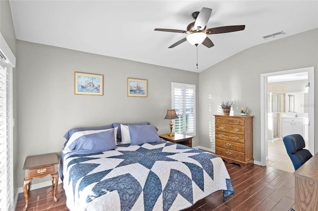 bedroom with baseboards, visible vents, dark wood finished floors, lofted ceiling, and ensuite bathroom