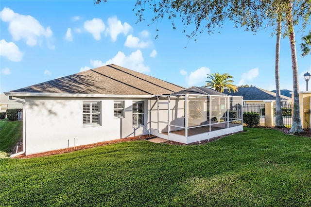 rear view of property featuring glass enclosure, roof with shingles, fence, a yard, and stucco siding