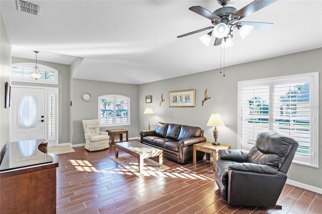 living room featuring wood finish floors, visible vents, a textured ceiling, and baseboards