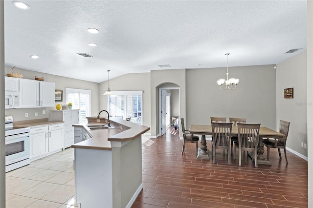 kitchen with arched walkways, white appliances, a sink, visible vents, and white cabinets