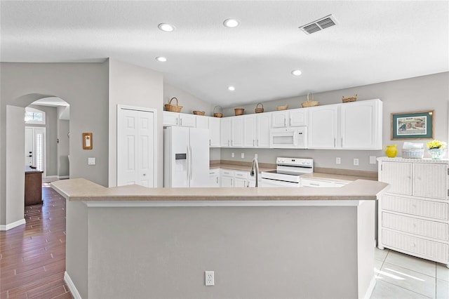 kitchen featuring white appliances, visible vents, arched walkways, light countertops, and white cabinetry