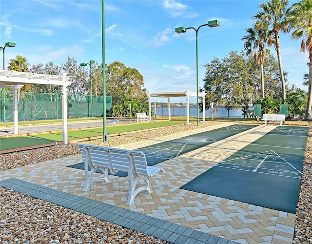 view of property's community featuring fence and shuffleboard