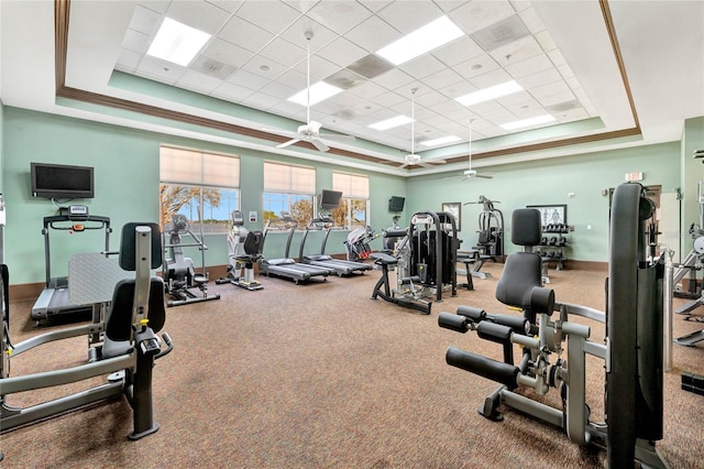 gym featuring baseboards, a raised ceiling, and a ceiling fan