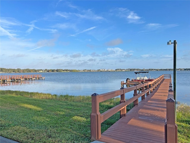 view of dock with a lawn and a water view