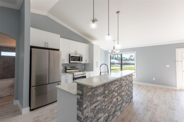 kitchen featuring white cabinetry, decorative light fixtures, a center island with sink, appliances with stainless steel finishes, and light wood-type flooring