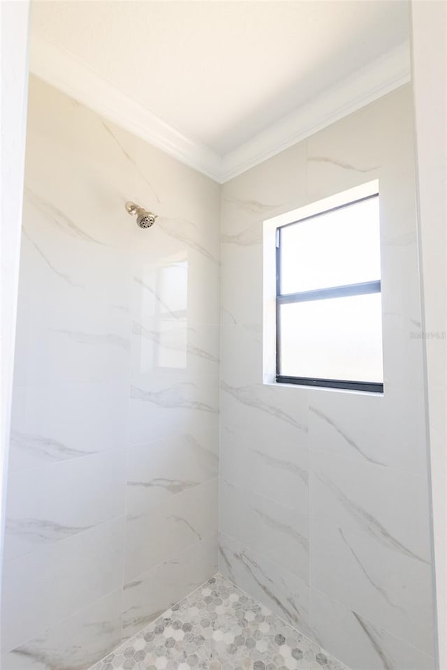 bathroom with a tile shower and ornamental molding