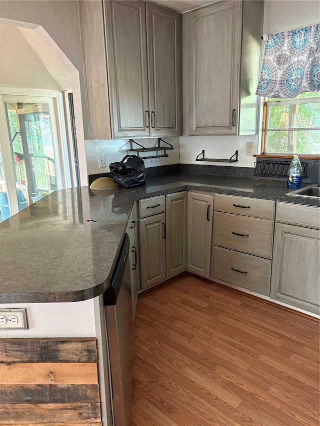 kitchen featuring kitchen peninsula, a wealth of natural light, dishwasher, and hardwood / wood-style flooring