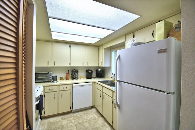 kitchen featuring sink, white appliances, and cream cabinetry