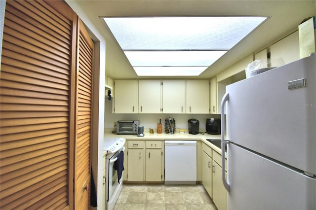 kitchen with cream cabinetry, stainless steel fridge, and white dishwasher