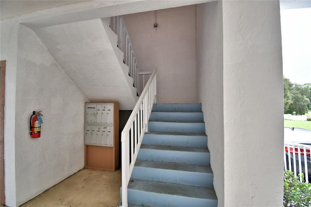 stairs with concrete flooring and a mail area