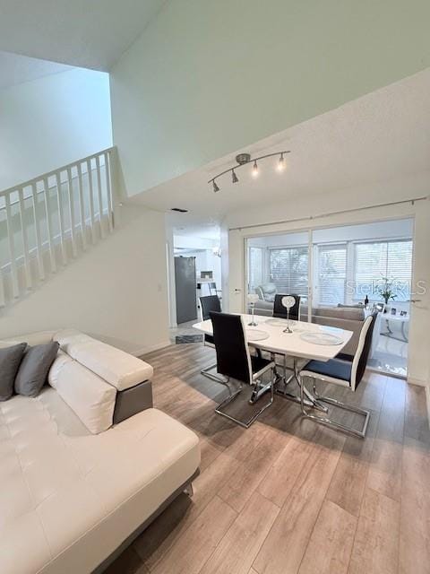 dining area with high vaulted ceiling and hardwood / wood-style flooring