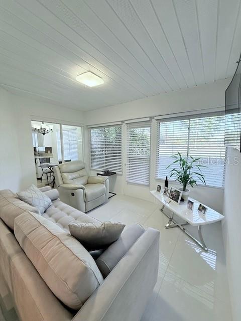 living room with a chandelier, light tile patterned floors, and wooden ceiling