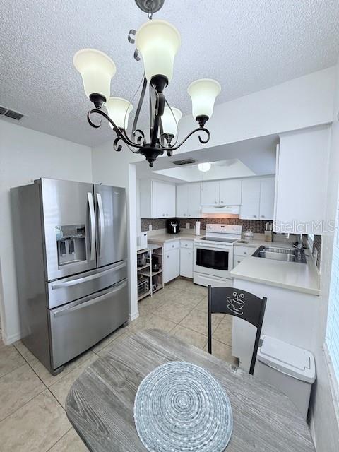 kitchen with sink, electric range, an inviting chandelier, white cabinets, and stainless steel fridge with ice dispenser