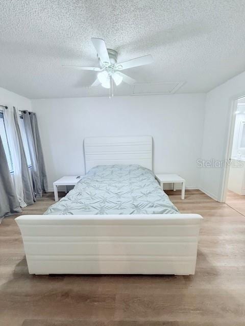 bedroom featuring hardwood / wood-style floors, ceiling fan, and a textured ceiling