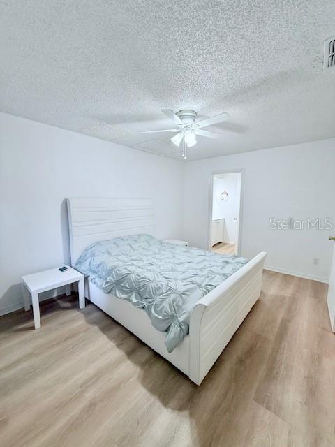 bedroom featuring ceiling fan, hardwood / wood-style floors, and a textured ceiling