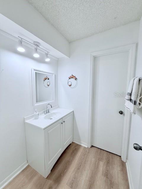 bathroom with hardwood / wood-style flooring, vanity, and a textured ceiling