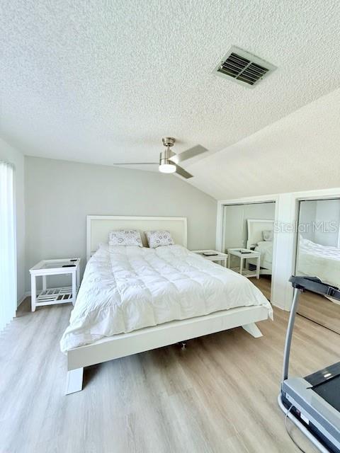 bedroom featuring hardwood / wood-style floors, a textured ceiling, ceiling fan, and lofted ceiling