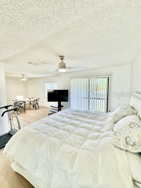 bedroom featuring access to exterior, a textured ceiling, and ceiling fan