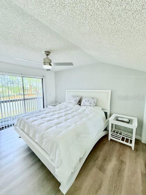 bedroom featuring access to exterior, ceiling fan, wood-type flooring, and a textured ceiling