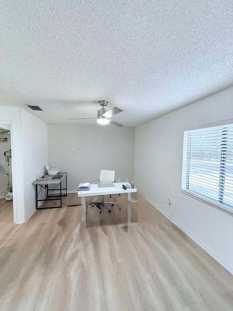 office space with ceiling fan, a textured ceiling, and light hardwood / wood-style flooring