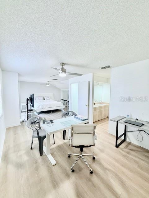 interior space featuring a textured ceiling, light wood-type flooring, and ensuite bath