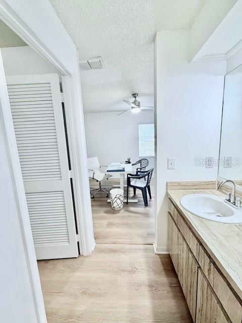 bathroom with hardwood / wood-style flooring, ceiling fan, a textured ceiling, and vanity