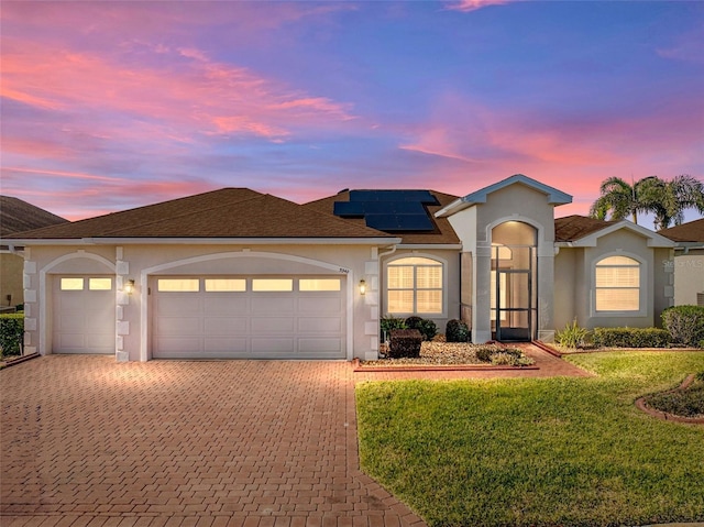 view of front of home featuring a lawn, a garage, and solar panels