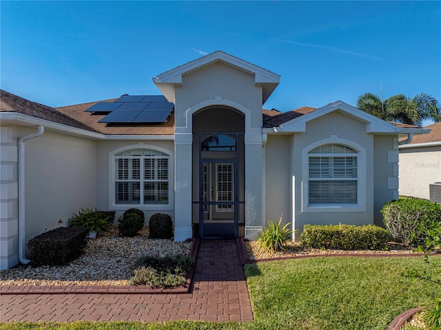 view of front of home with a front yard and solar panels