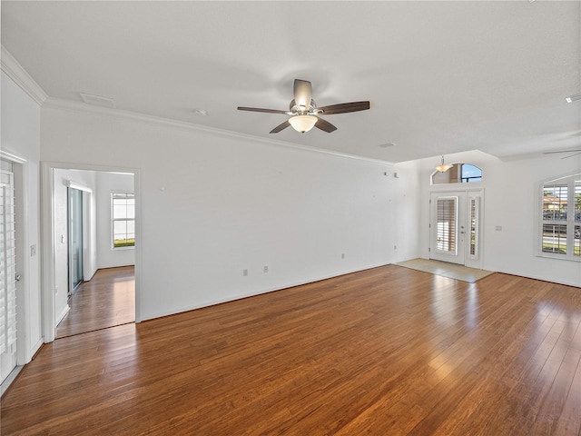 unfurnished living room featuring ceiling fan, wood-type flooring, and ornamental molding