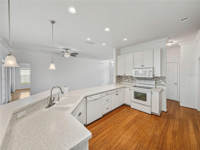 kitchen featuring kitchen peninsula, white appliances, sink, decorative light fixtures, and white cabinets