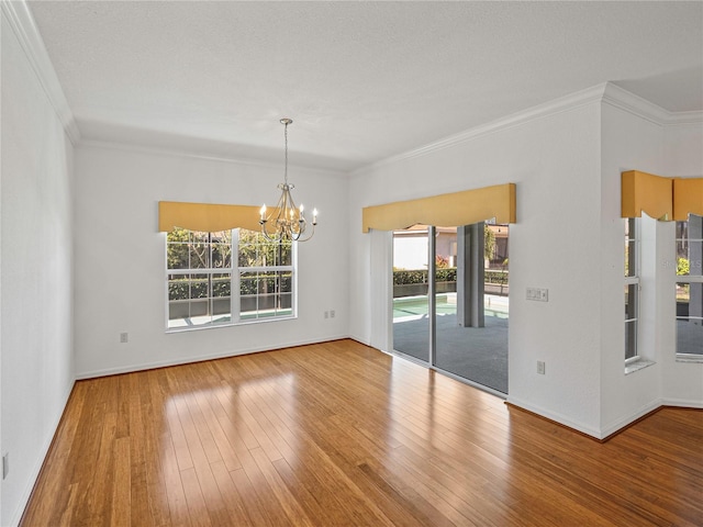 unfurnished room featuring hardwood / wood-style flooring, crown molding, and an inviting chandelier