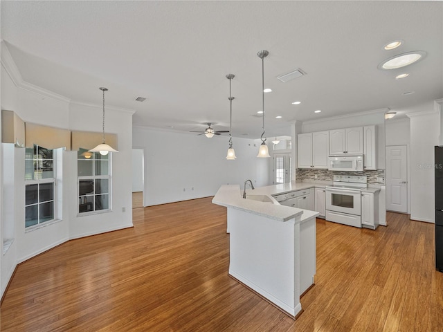 kitchen with pendant lighting, white appliances, white cabinets, light hardwood / wood-style flooring, and kitchen peninsula