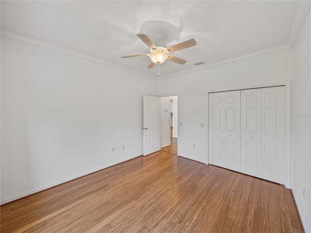 unfurnished bedroom featuring a closet, light hardwood / wood-style flooring, ceiling fan, and ornamental molding