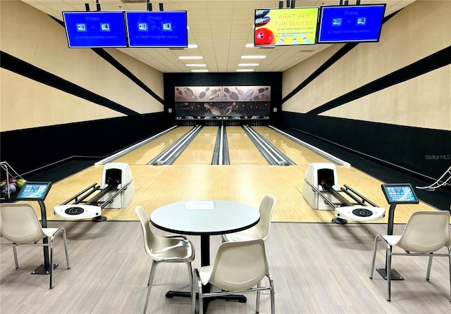 game room with bowling, wood-type flooring, and a paneled ceiling