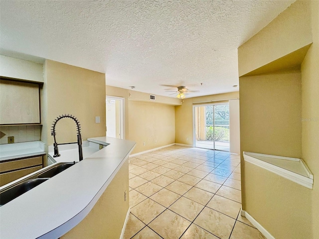 kitchen featuring light tile patterned flooring, a textured ceiling, ceiling fan, and sink