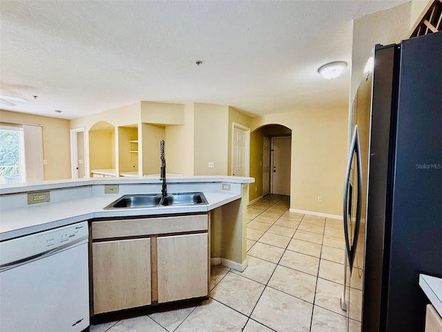 kitchen featuring stainless steel refrigerator, dishwasher, sink, a textured ceiling, and light tile patterned floors