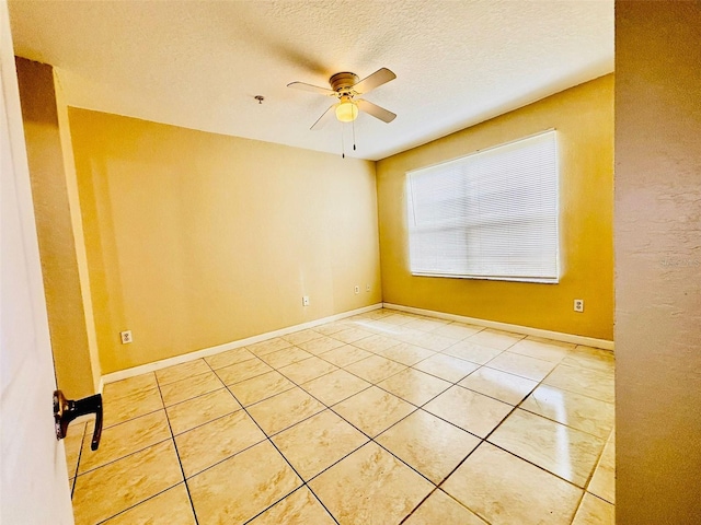 empty room with tile patterned floors, ceiling fan, and a textured ceiling