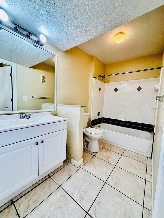 full bathroom with a textured ceiling, tiled shower / bath combo, vanity, tile patterned flooring, and toilet