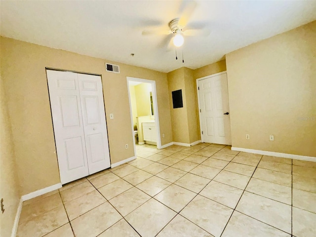 unfurnished bedroom with ceiling fan, light tile patterned floors, and ensuite bathroom