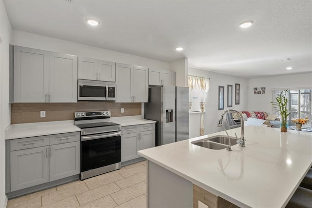 kitchen featuring gray cabinetry, decorative backsplash, sink, and appliances with stainless steel finishes