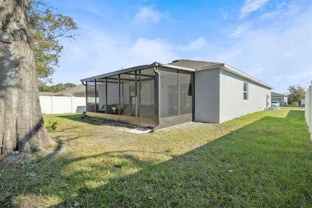 rear view of property featuring a sunroom and a lawn