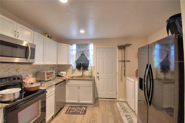 kitchen featuring backsplash, sink, light hardwood / wood-style flooring, white cabinetry, and stainless steel appliances