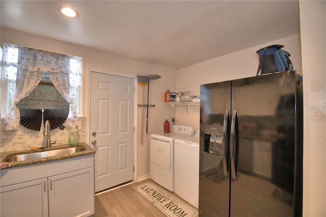 washroom featuring washing machine and clothes dryer, sink, cabinets, and light hardwood / wood-style flooring