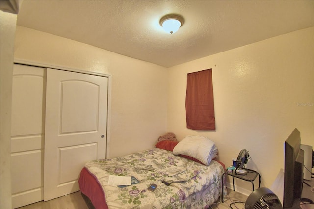 bedroom with a closet, a textured ceiling, and light hardwood / wood-style flooring