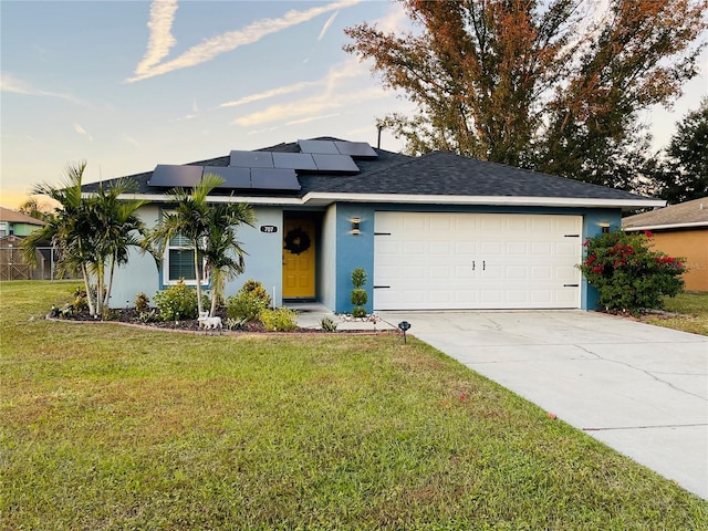 view of front facade featuring solar panels, a garage, and a yard