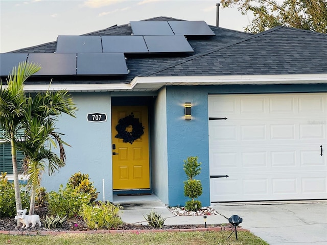 doorway to property featuring solar panels and a garage