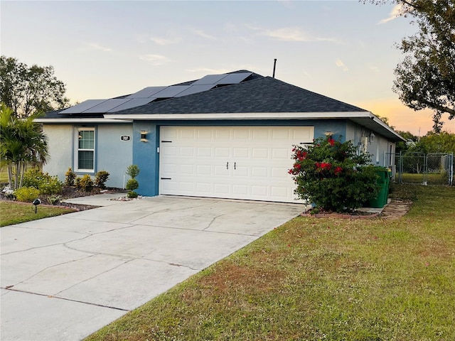 view of front of property featuring solar panels, a garage, and a yard