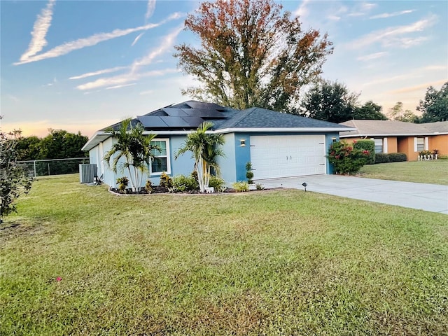 single story home with a lawn, solar panels, cooling unit, and a garage