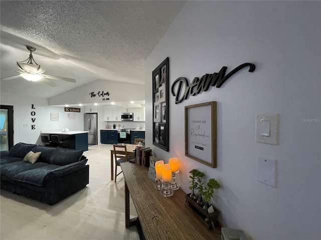 living room with ceiling fan, lofted ceiling, and a textured ceiling